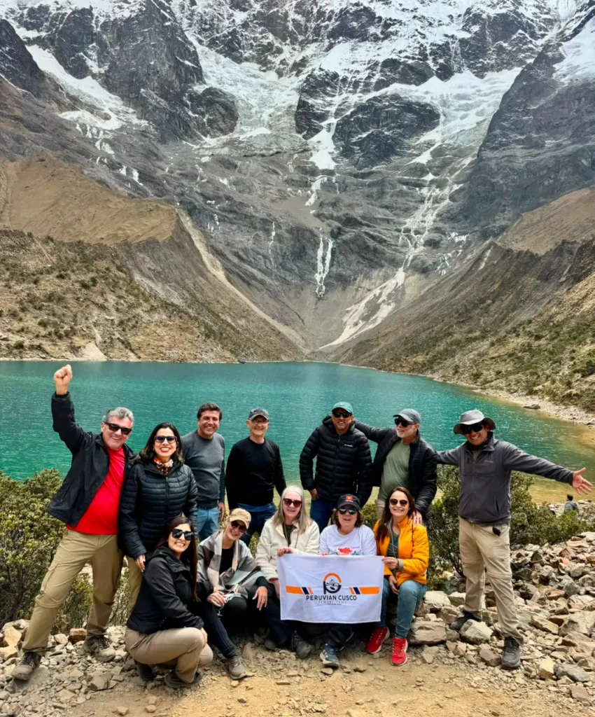 Group of hikers on the Humantay Lake tour standing beside the turquoise glacial lagoon